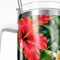 A close-up view of a red hibiscus flower on a clear glass container, with a handle visible on the left side.